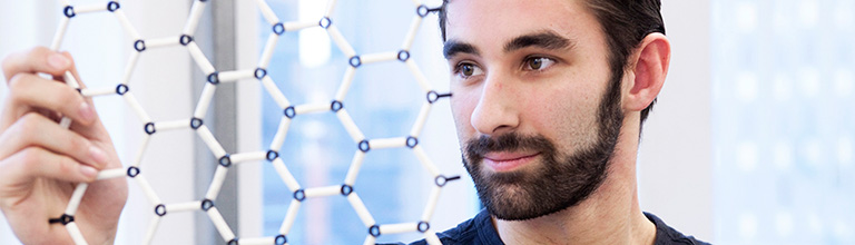 student looking at a model of graphene