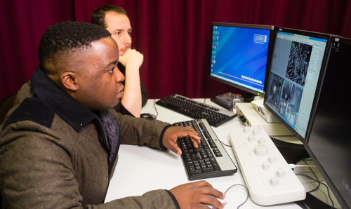 Two researchers working on computer in red curtained room